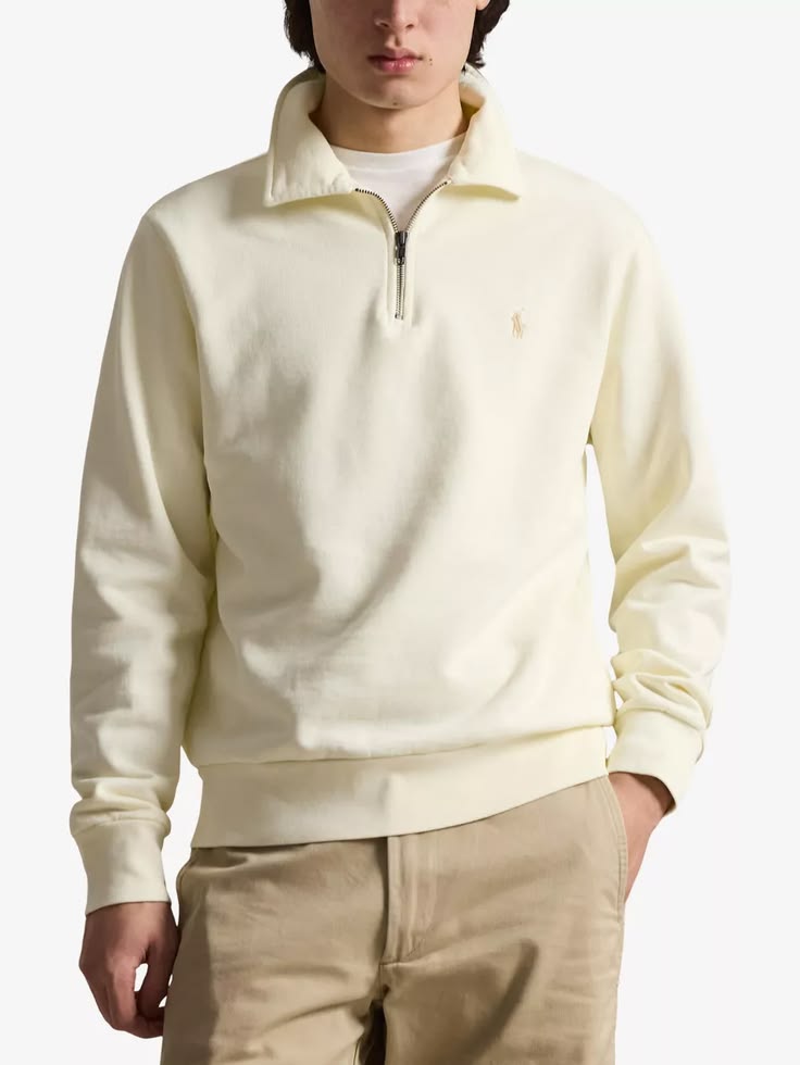 A model wearing a cream-colored quarter-zip pullover sweater with a small embroidered polo player logo on the chest, paired with khaki pants against a light gray background.