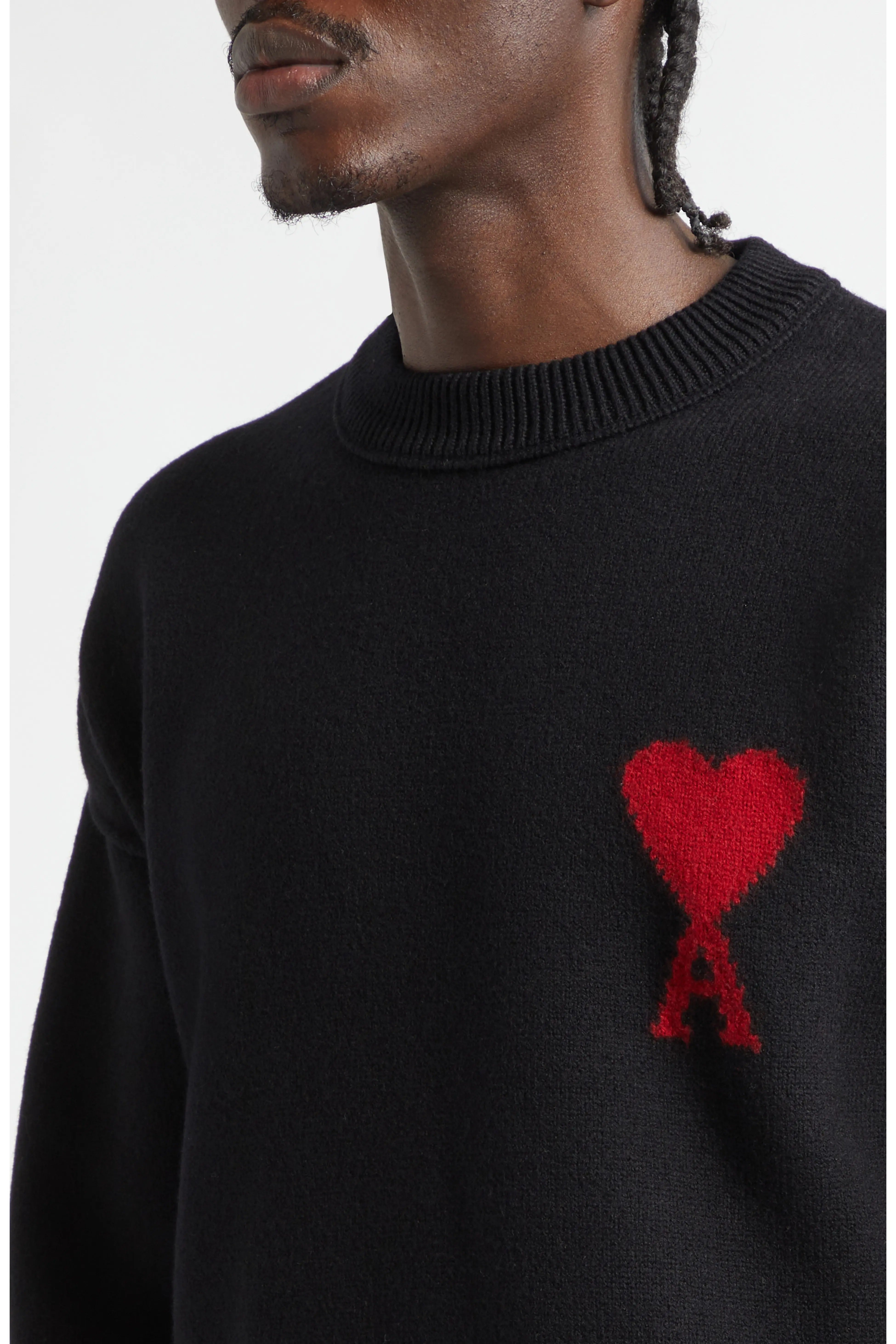 Black sweater with a red heart and 'A' design worn by a person.