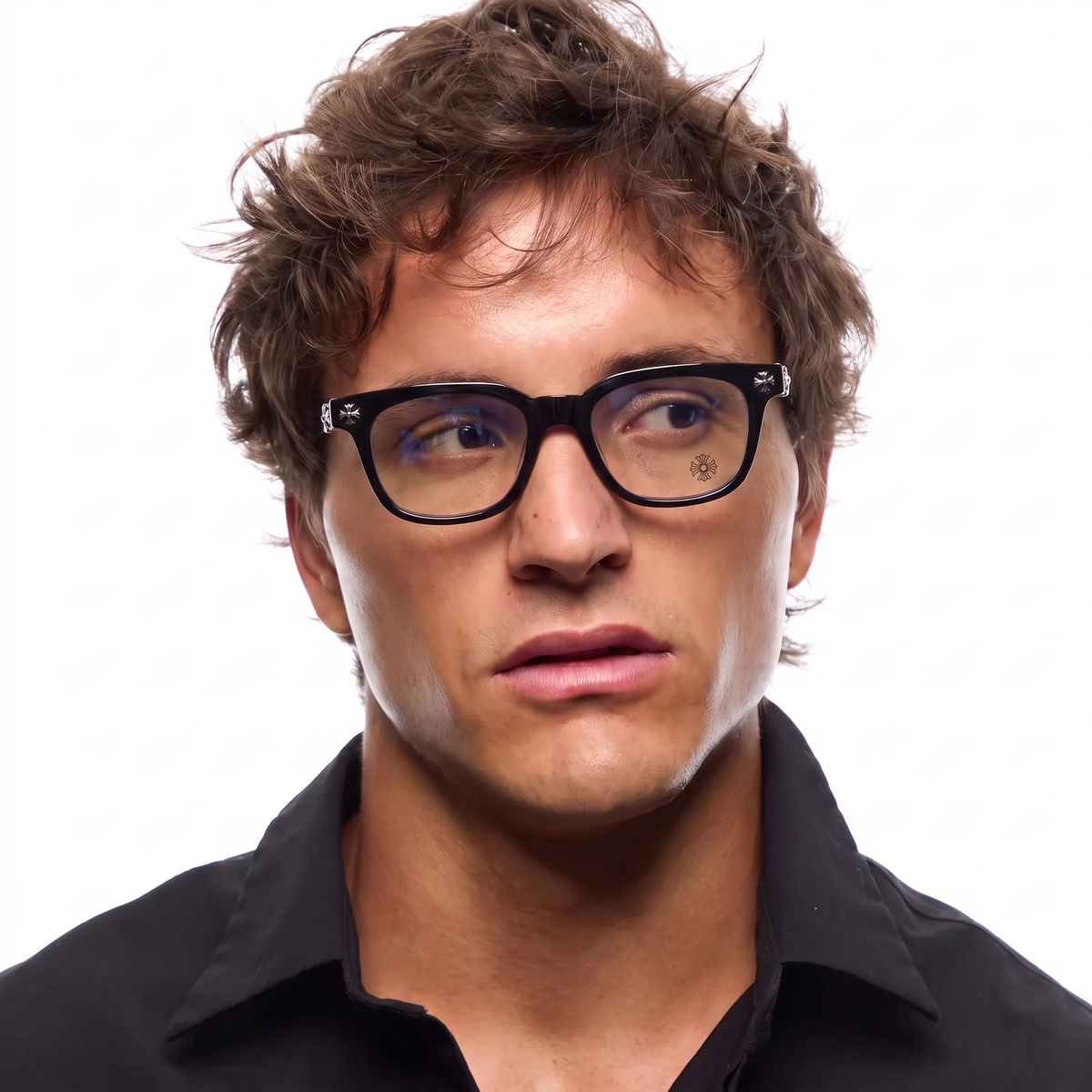 A close-up portrait of a man with brown hair wearing black rectangular eyeglasses and a black collared shirt against a plain white background.
