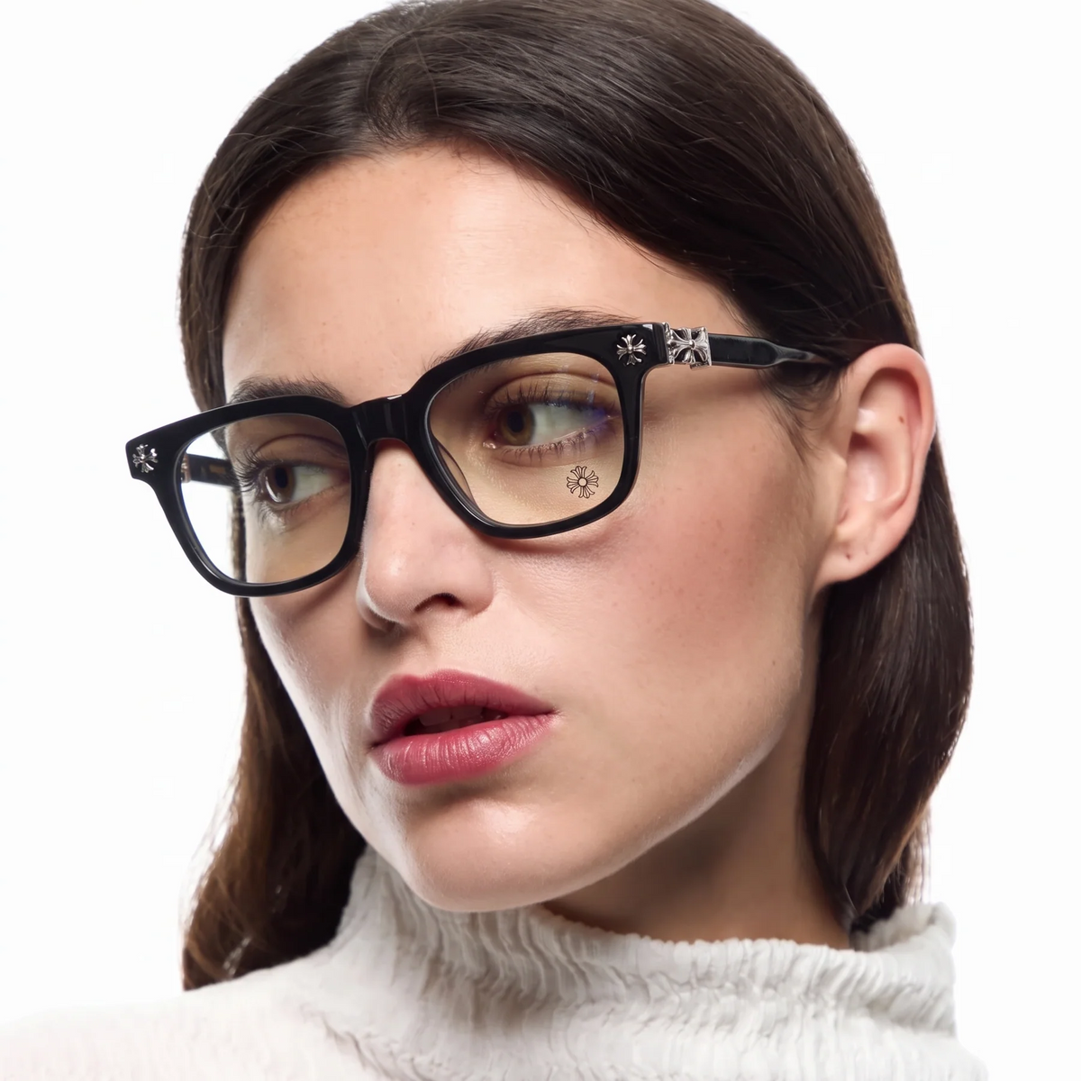 A close-up of a woman wearing black cat-eye eyeglasses with small white floral details on the temples, set against a clean white background.