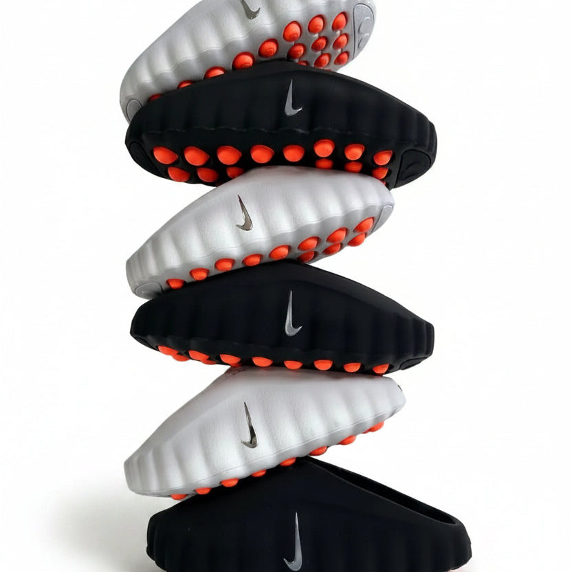 Stack of black and white sandals with red accents on a light gray background
