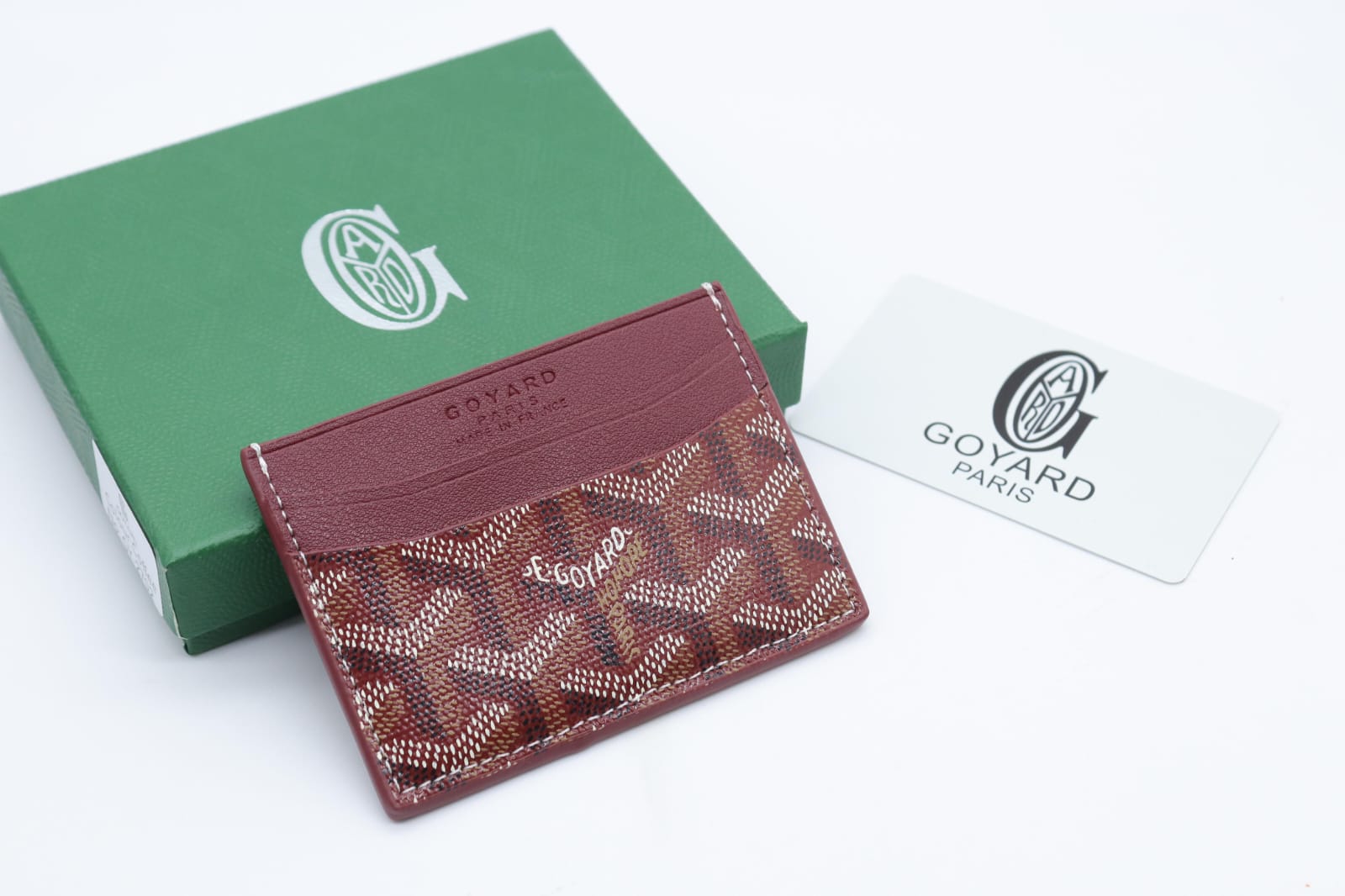 Goyard cardholder with green box and white card on a light gray background