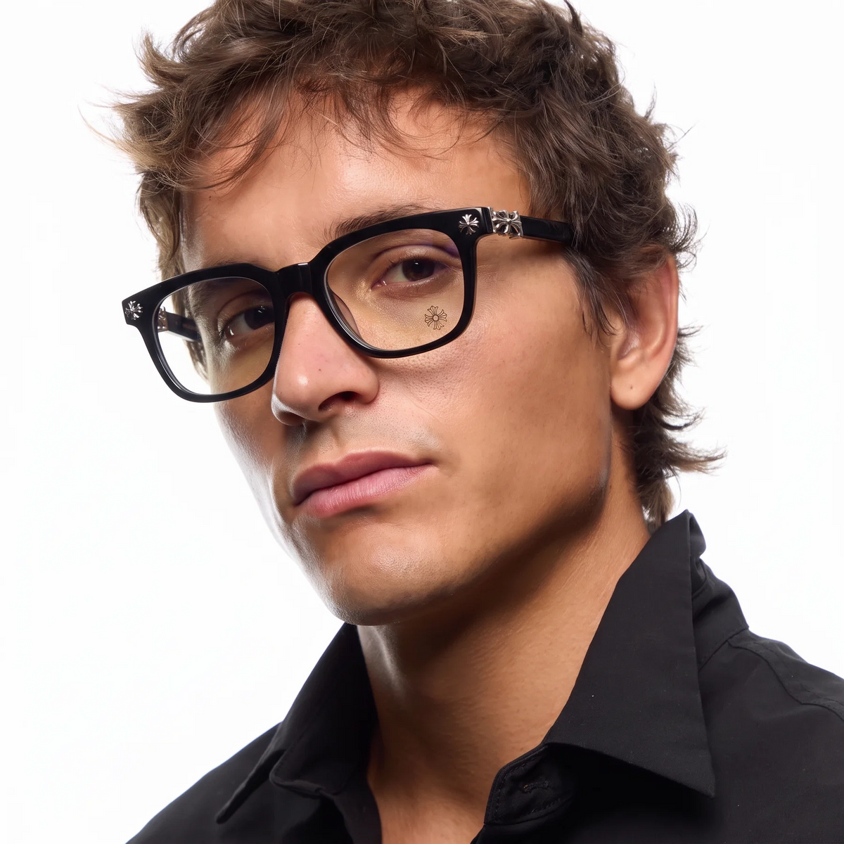 A close-up portrait of a man with brown hair wearing black square eyeglasses with decorative silver details on the temples and a black collared shirt, set against a plain white background.